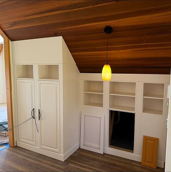 White built-in cabinetry and open shelving under a cedar ceiling