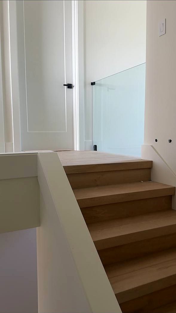 Frameless glass railing at a maple stair landing
