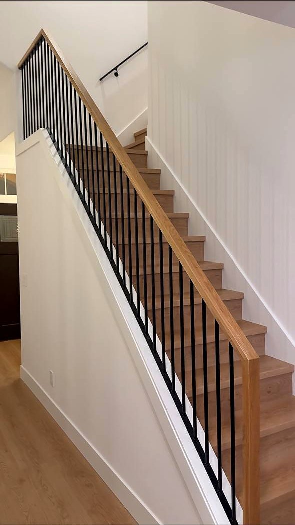 Oak handrail with black iron balusters on a full stair run
