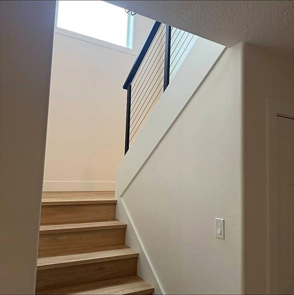 Oak stairs under a skylight with cable railing above