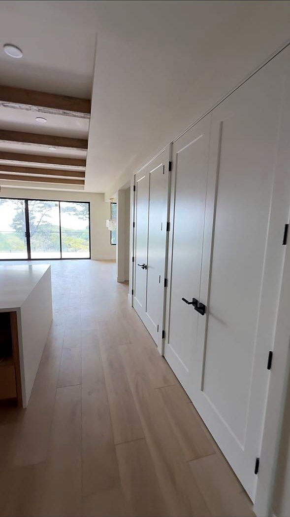 White shaker doors along a hallway under exposed beams